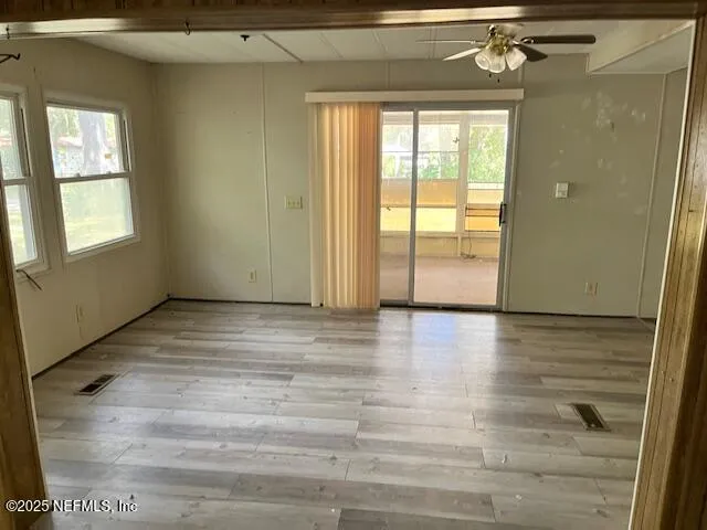 a view of empty room with wooden floor and fan