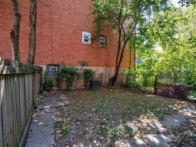 a view of a backyard with plants and wooden fence