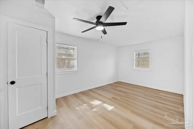 a view of empty room with wooden floor and ceiling fan