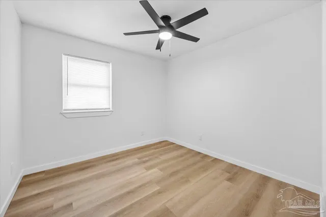 an empty room with a window and a fan