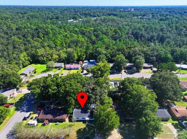 a view of a wooden house with a big yard and large trees