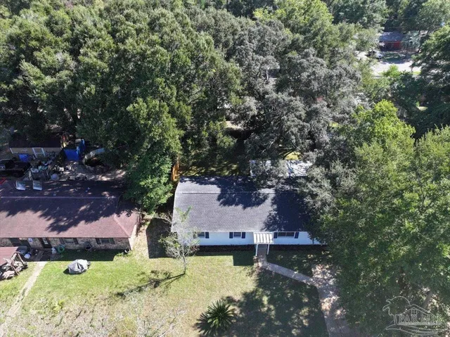 an aerial view of a house with swimming pool a yard and a large tree