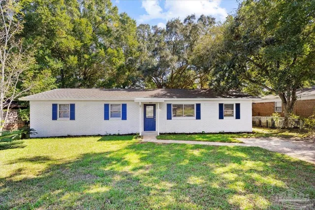 a house that is sitting in the grass with large trees