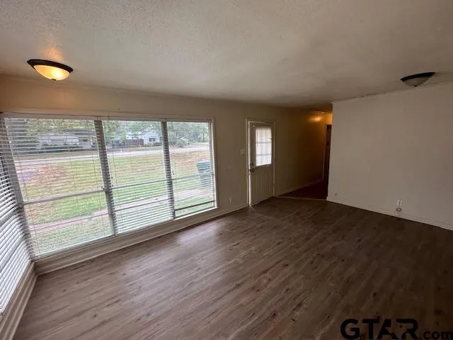 an empty room with wooden floor and windows
