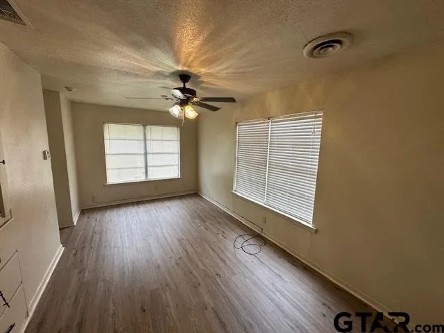 a view of an empty room with a window and wooden floor