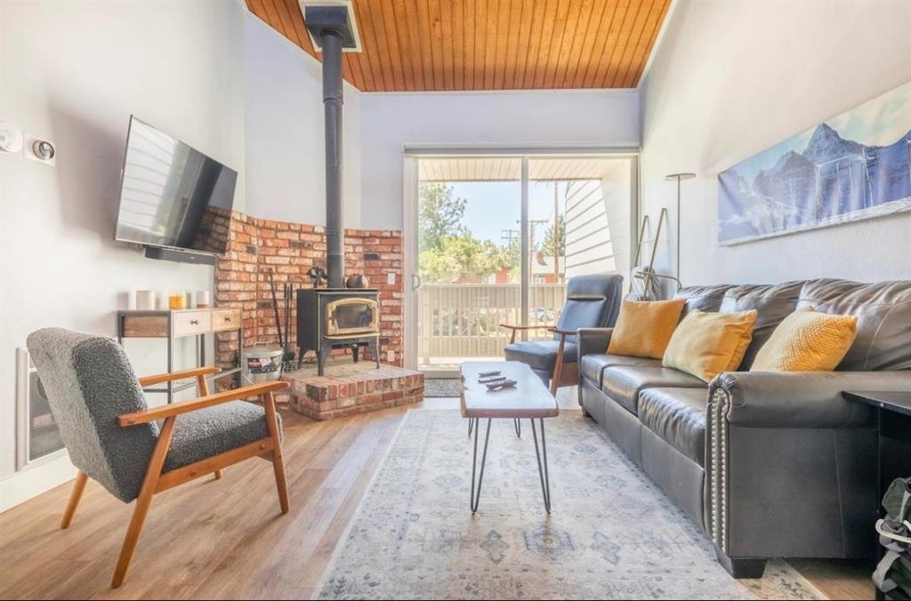 Living area featuring a wood stove, a high wood ceiling, and wood finished floors