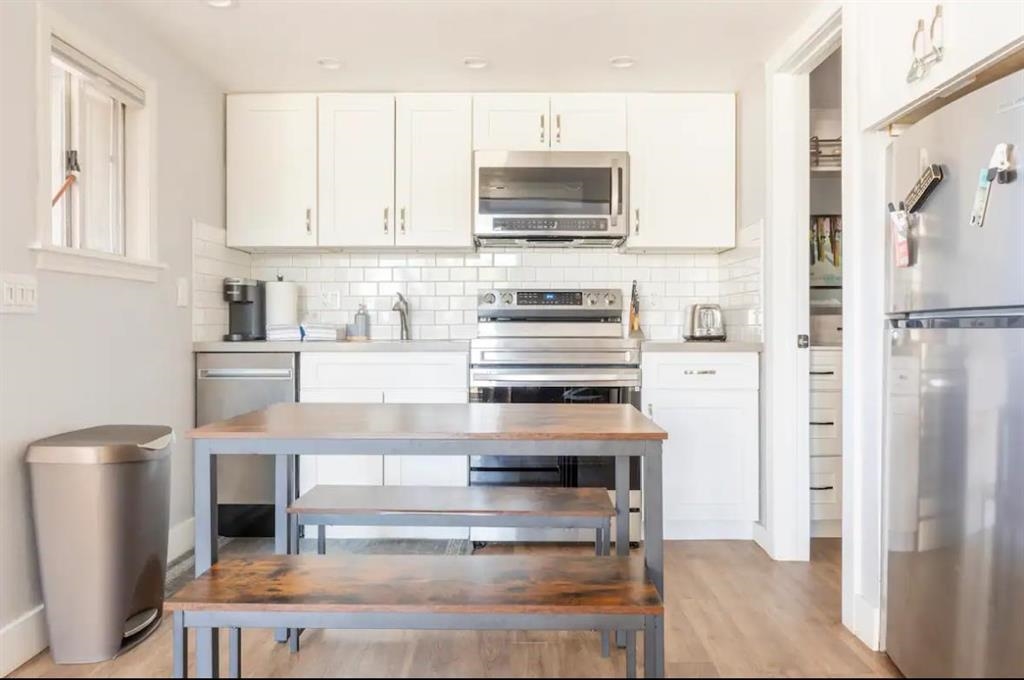 137 Laurel Mountain Road, Unit 418 Mammoth Lakes, CA 93546 - Photo 5 of 23 Kitchen featuring stainless steel appliances, white cabinetry, tasteful backsplash, and light wood-style floors