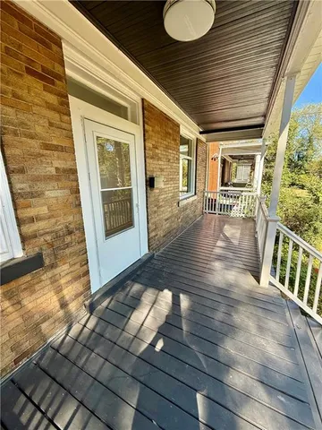 a view of a porch with wooden floor and floor to ceiling window