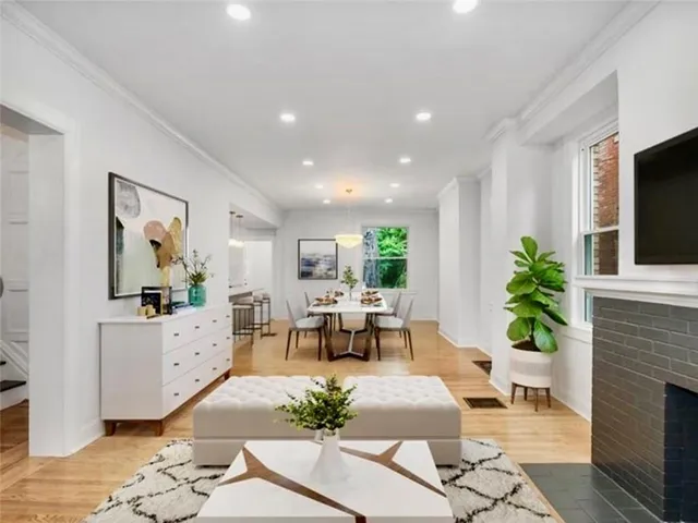 a living room with furniture a fireplace and a dining table with garden view