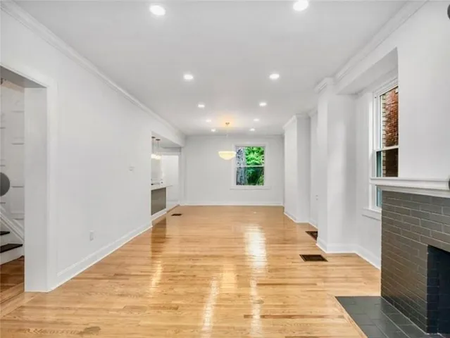 a view of an empty room with wooden floor and a fireplace