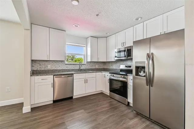 a kitchen with stainless steel appliances granite countertop a refrigerator and a stove top oven