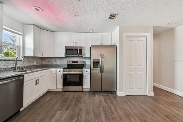 a kitchen with granite countertop a refrigerator and a stove top oven