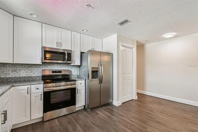 a kitchen with wooden floors and stainless steel appliances