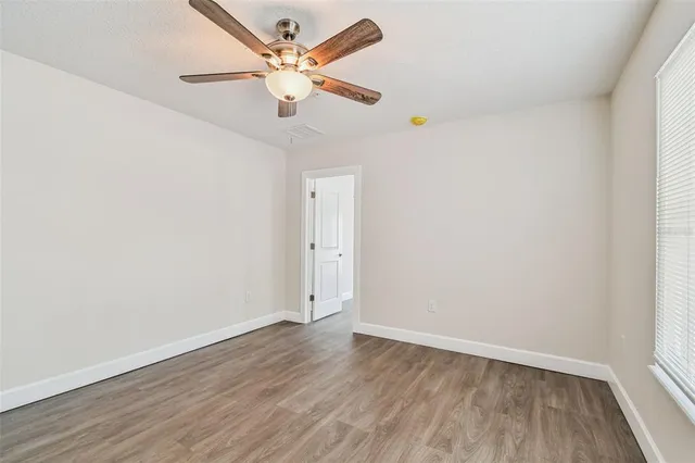 an empty room with wooden floor and fan
