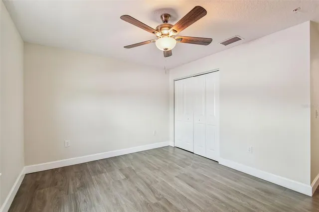 an empty room with wooden floor and ceiling fan