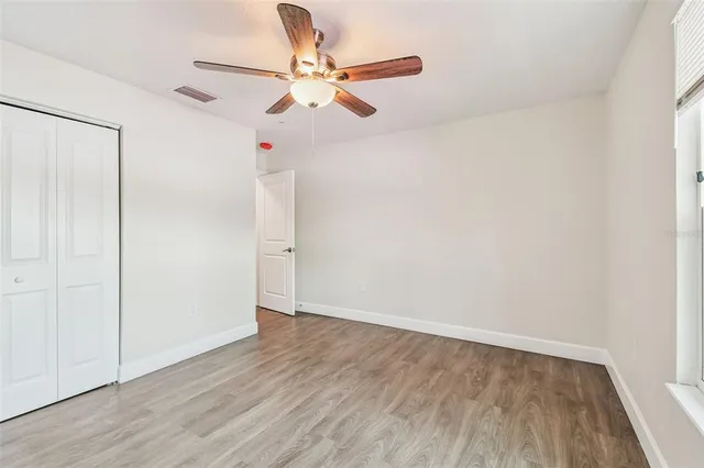 an empty room with wooden floor ceiling fan