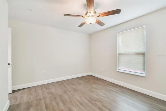 an empty room with a window and a fan