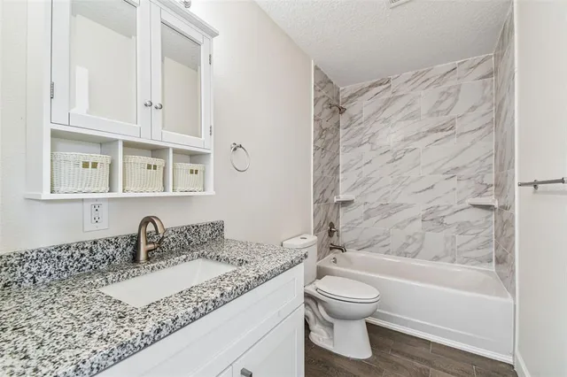a bathroom with a granite countertop sink toilet a mirror and shower