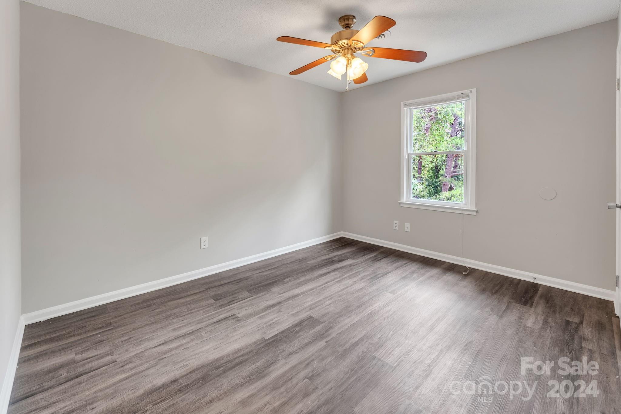 1018 Palmyra Drive Tega Cay, SC 29708 - Photo 29 of 36 an empty room with wooden floor chandelier fan and windows