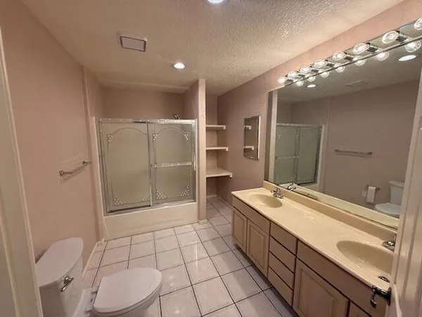a spacious bathroom with a granite countertop sink a toilet a mirror and shower