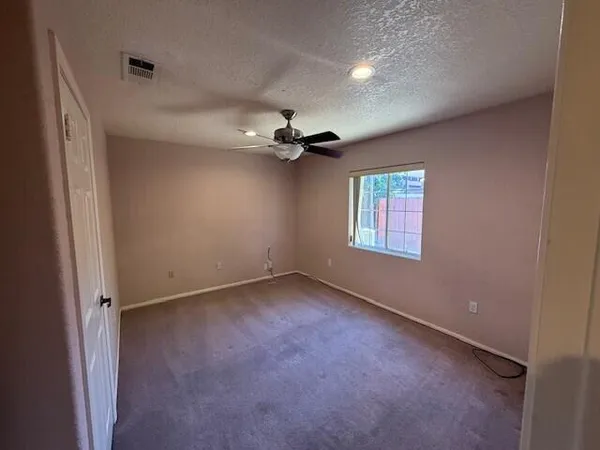 an empty room with a ceiling fan and window