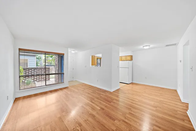 a view of an empty room with wooden floor and a window