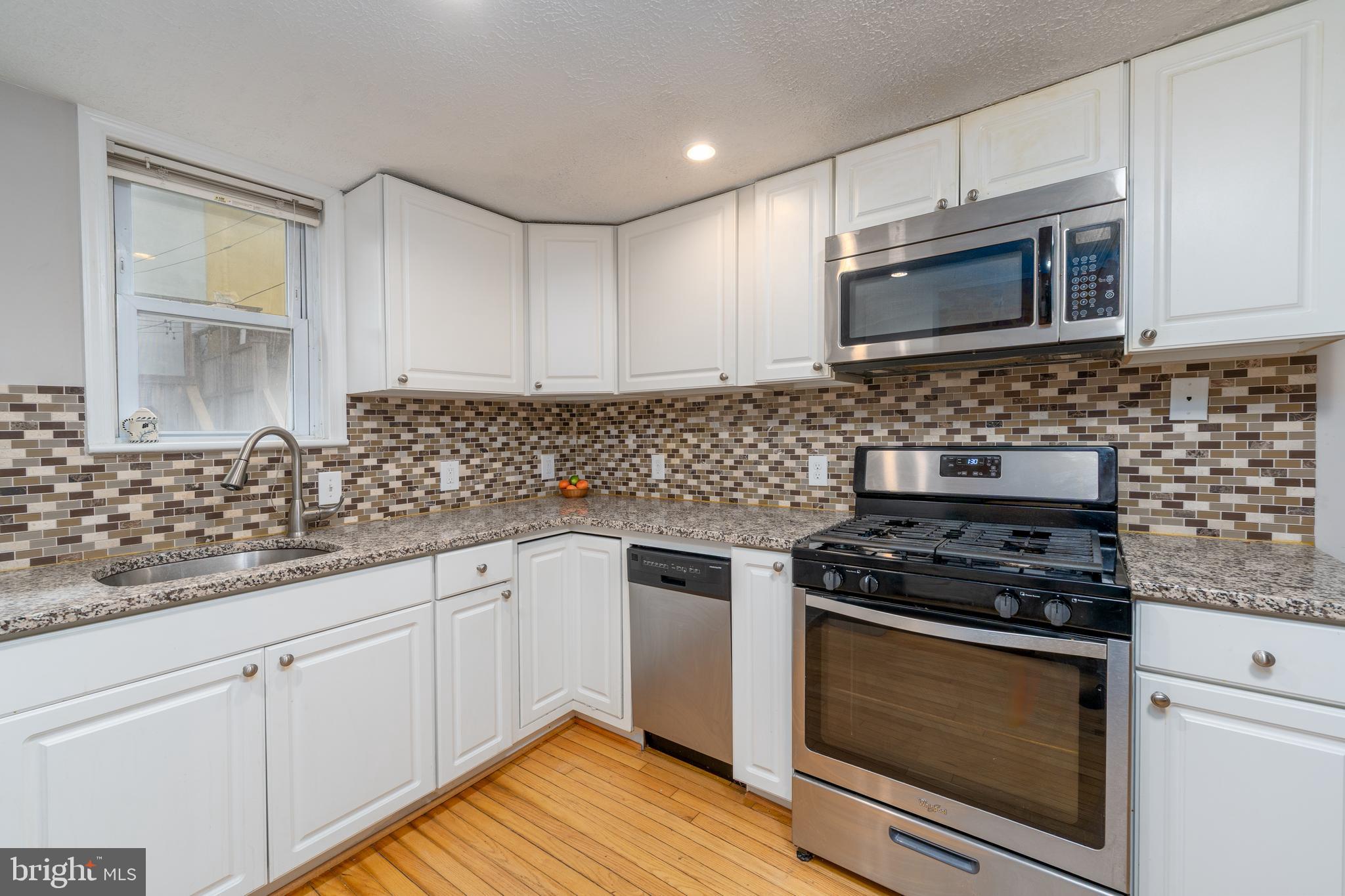 1627 Olive Street Baltimore, MD 21230 - Photo 11 of 22 a kitchen with granite countertop white cabinets stainless steel appliances and a sink