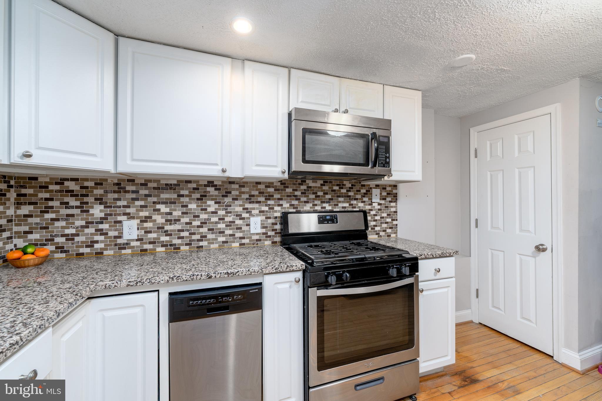 1627 Olive Street Baltimore, MD 21230 - Photo 10 of 22 a kitchen with granite countertop a sink stove and microwave