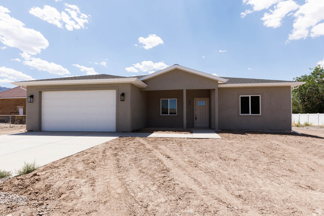 51 West 500 South Monroe, UT 84754 - Photo 4 of 41 Contemporary single-story residence featuring a two-car garage with a white panel door, stucco exterior finish, and a covered entryway
