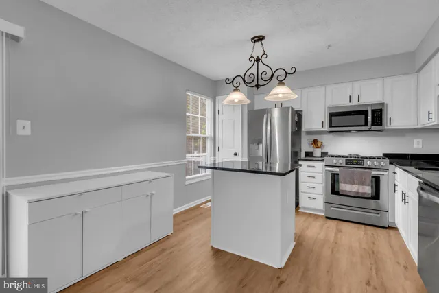 a kitchen with stainless steel appliances granite countertop white cabinets a sink a stove and dishwasher