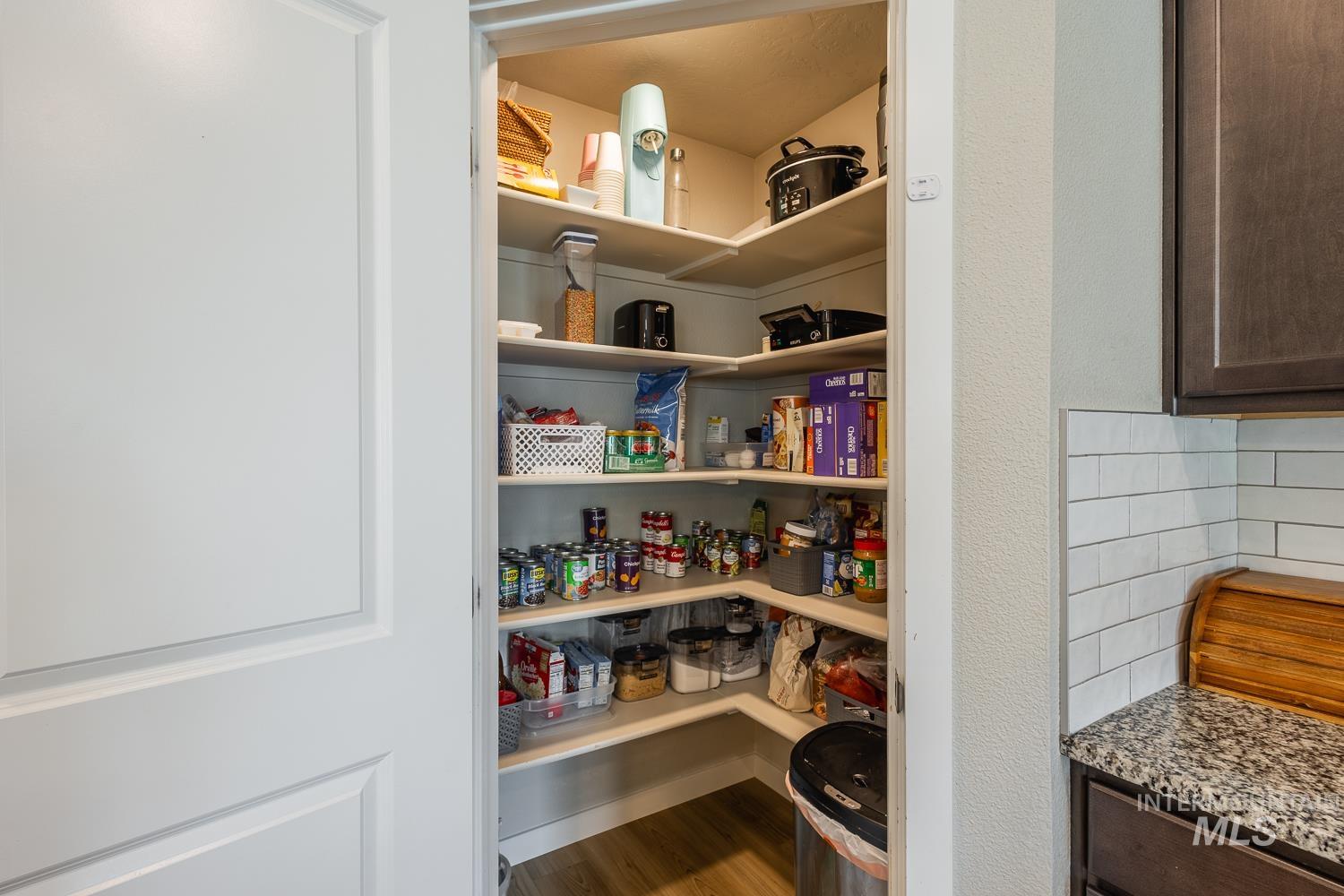 12623 Shadow Peak Street Caldwell, ID 83607 - Photo 22 of 50 Corner pantry with multiple levels of shelving, wood-finish flooring, and a white paneled door