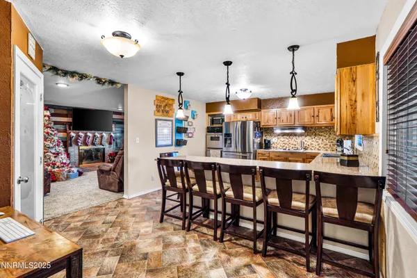 a kitchen with stainless steel appliances kitchen island granite countertop a table chairs and a refrigerator