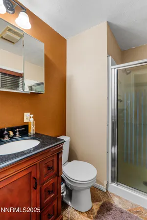 a bathroom with a granite countertop sink and a toilet