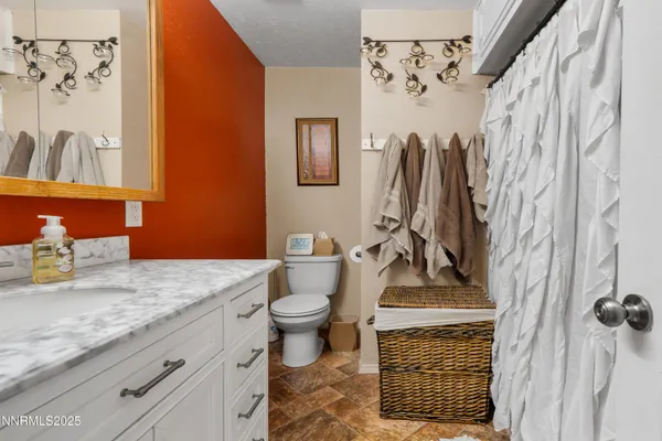 a bathroom with a granite countertop sink a toilet and a shower curtain