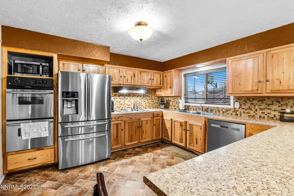 a kitchen with granite countertop a refrigerator stove top oven and sink