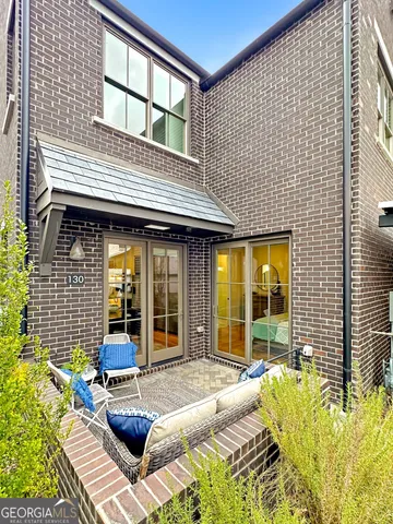 a view of brick house with large windows and plants