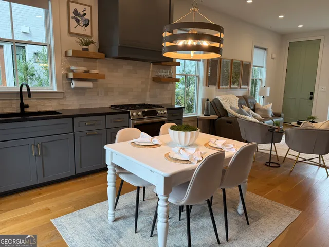 a kitchen with stainless steel appliances granite countertop a sink a stove a dining table and chairs