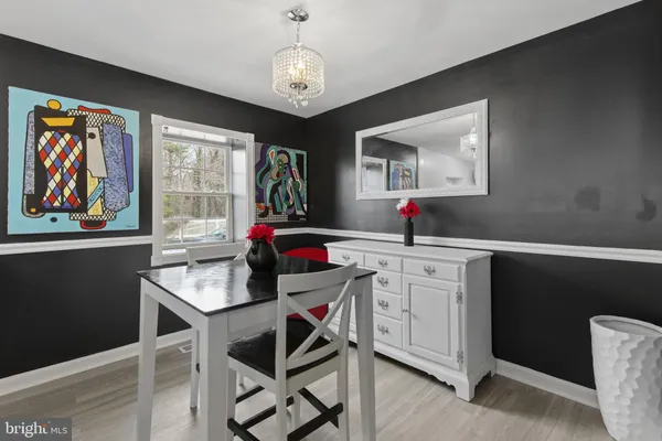 a dining room with wooden floor a chandelier a wooden table and chairs