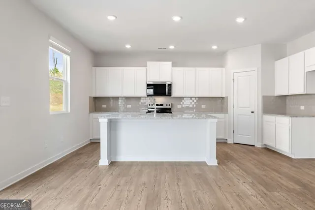 a kitchen with granite countertop white cabinets and wooden floor