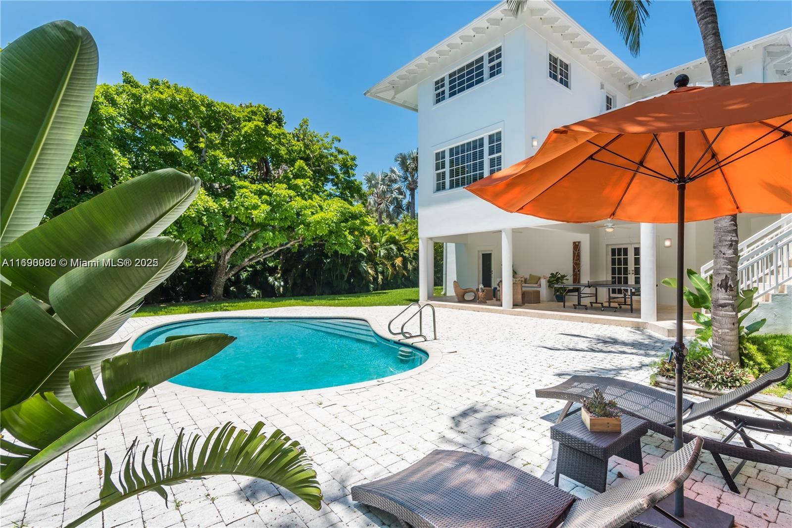 325 Pacific Road Key Biscayne, FL 33149 - Photo 22 of 31 a view of pool with lawn chairs under an umbrella