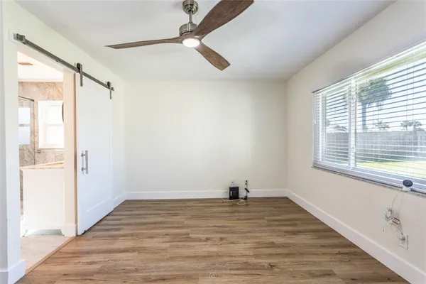a view of empty room with wooden floor and fan