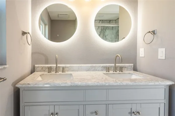 a bathroom with double vanity and a mirror