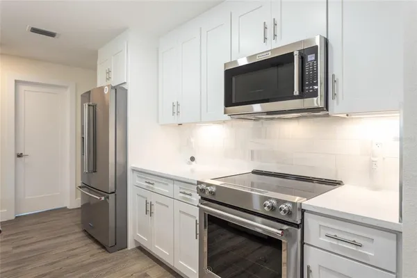 a kitchen with stainless steel appliances white cabinets and a stove top oven