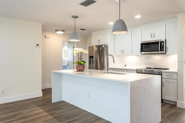 a kitchen with kitchen island a sink stainless steel appliances and cabinets