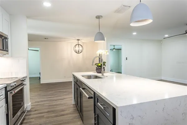 a kitchen with a sink a chandelier stainless steel appliances and cabinets