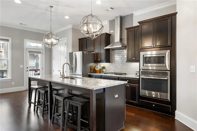 a kitchen with stainless steel appliances granite countertop a kitchen island hardwood floor and a view of living room
