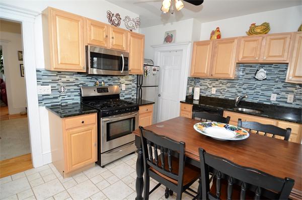 a kitchen with stainless steel appliances kitchen island granite countertop a sink a stove a microwave cabinets and a dining table