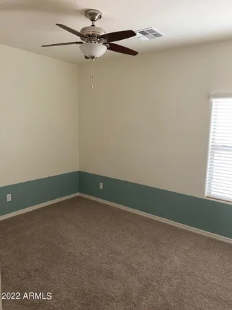 an empty room with a fan & a window