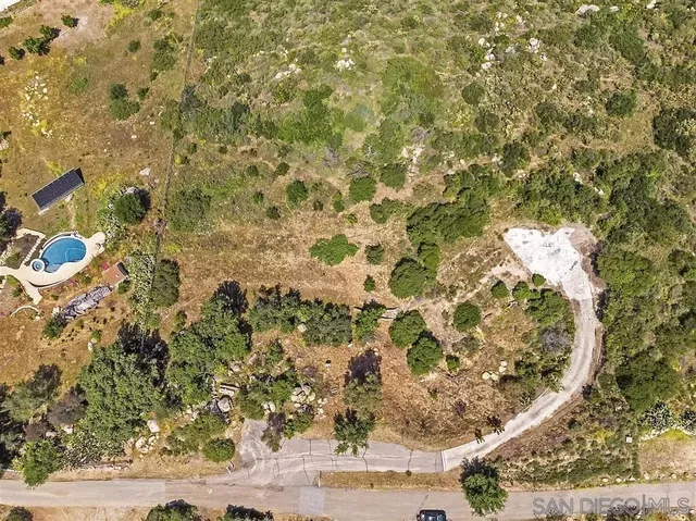 a view of a dry yard with wooden fence