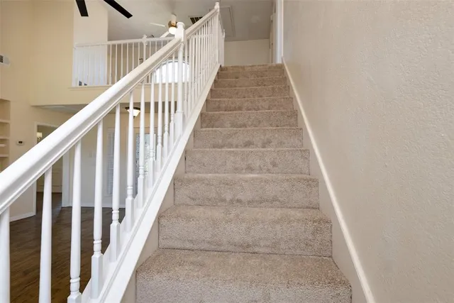 a view of staircase with railing and white walls
